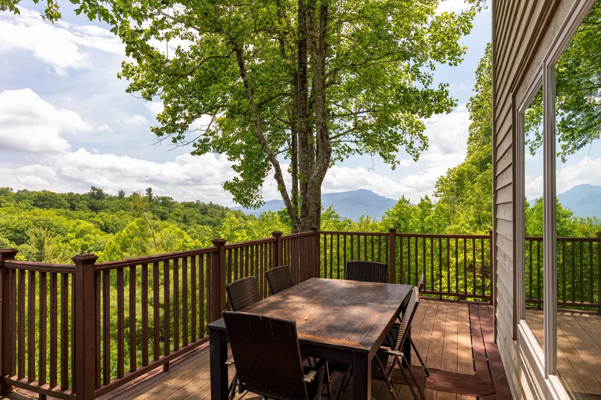 An inviting outdoor dining scene with a rustic table set on a deck overlooking stunning mountain views and surrounded by towering trees. The space is ideal for meals, picnics, or just relaxing outdoors, echoing the family-friendly, activity-rich spirit of the High Country.