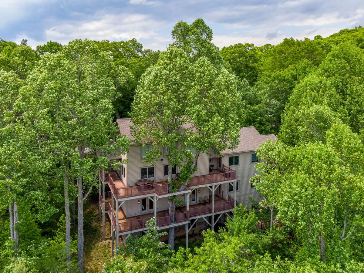 An exterior shot of the home surrounded by tall trees, with balconies visible and a tranquil, welcoming mood. The image hints at privacy, space, and the ability to enjoy nature walks or relax while soaking in the mountain atmosphere.