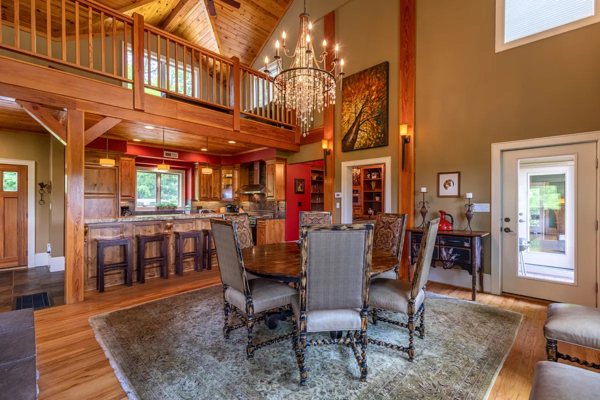 A cozy dining area accented by a solid wood table beneath a glowing chandelier, with the adjacent kitchen visible in the background. The setting is intimate yet spacious, perfect for hosting dinners or family meals, and subtly showcases the interconnectedness of the living spaces.